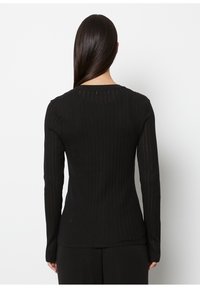 Czarna prążkowana bluzka z długim rękawem o dopasowanym kroju, z pionowymi paskami i okrągłym dekoltem, wykonana z miękkiego, elastycznego materiału.