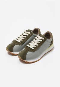 Zapatillas que combinan ante verde olivo y tela gris claro, con un acento texturizado en forma de ondas, cordones blancos y suela de goma.