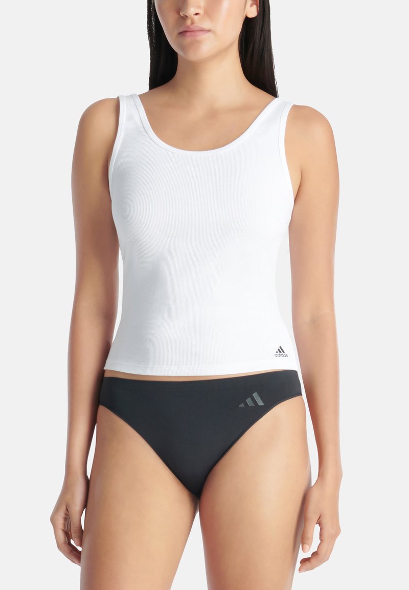 Biała, żebrowana bluzka na ramiączkach z szerokimi paskami, połączona z czarnymi dolnymi częściami bikini z szarymi akcentami logo po bokach.