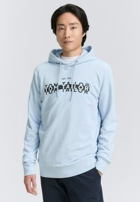 Világoskék kapucnis pulóver elülső zsebbel, húzózsinóros kapucnival és fekete szöveges logóval. Simaszerkezetű anyag, testhezálló fazon és bordás széllel.