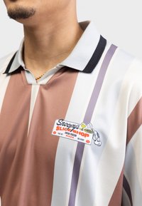 Short-sleeve polo shirt in shades of brown, gray, and lavender, featuring a black collar and a colorful "Snoopy's Slice Shop" patch.