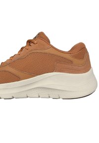 Scarpa da atletica marrone con tomaia in rete, dettagli in suede, suola bianca spessa e design a punta rotonda.