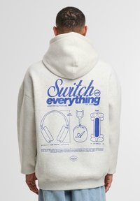 Hoodie in cotone grigio chiaro con una grande grafica blu sul retro, che presenta illustrazioni di cuffie e il testo "Spegni tutto."