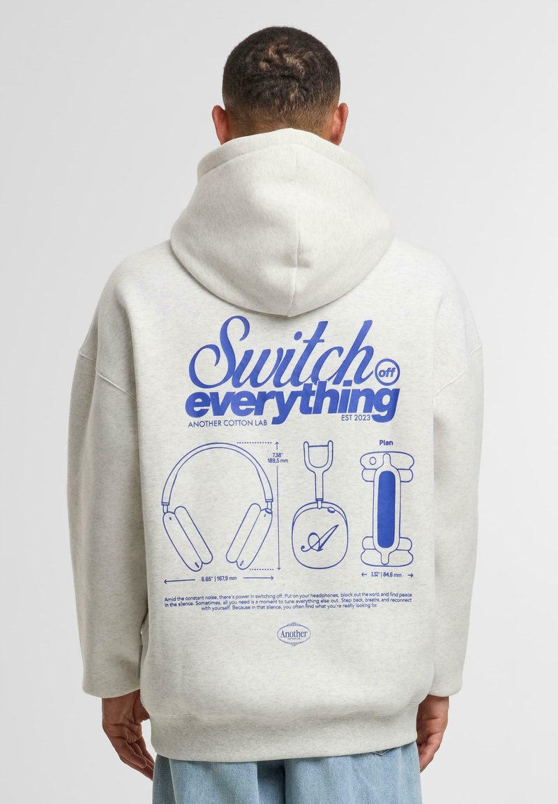 Hoodie in cotone grigio chiaro con una grande grafica blu sul retro, che presenta illustrazioni di cuffie e il testo "Spegni tutto."