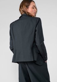 Zwarte gestreepte blazer met een op maat gemaakte design, notch revers en drie knopen op de mouwen, met een licht uitlopende achterzijde.