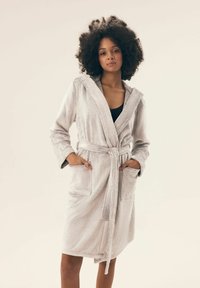 Jasnoszara pluszowa szlafrok z kapturem, wiązaniem w talii oraz przednimi kieszeniami. Miękka tekstura i długość do kolan zapewniają komfort i łatwość noszenia.