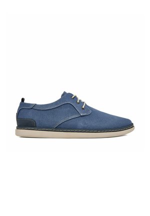 Zapato informal azul con cordones, suela beige y parche oscuro en el talón, hecho de tela texturizada, mostrado de lado sobre fondo blanco.