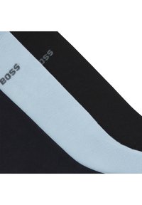 Tri par sokov v črni in svetlo modri barvi, z gladko teksturo in logotipom v sivi barvi na temnem materialu.