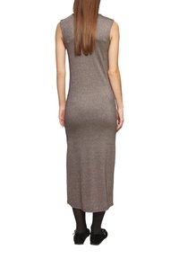 Długa, dopasowana, bezrękawna sukienka z metalicznej brązowej tkaniny, o długości do połowy łydki i gładkiej fakturze, zestawiona z czarnymi butami.