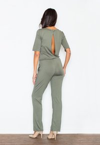 Jasnozielony kombinezon z okrągłym dekoltem i krótkimi rękawami, z odkrytymi plecami zapinanymi na guzik. Wykonany z miękkiego, elastycznego materiału.