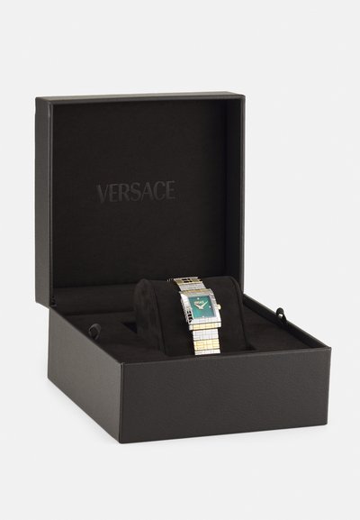 Sidabrinė ir auksinė tonuota stačiakampė laikrodžio forma su turkio spalvos ciferblatu, supakuota juodame dėkle su minkštu vidumi ir iškaltu "VERSACE" logotipu.
