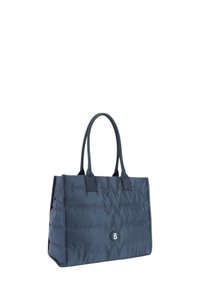 Marineblå quiltet tote bag med dobbelte håndtag, der har et syet zigzag-mønster og en rund logoaccent i midten.