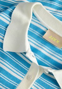 Blauw-wit gestreept gebreid poloshirt met witte kraag en knopen, met een beige label met gele tekst "JJXX".
