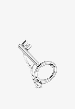 Anillo de plata diseñado como una llave vintage con un mango ovalado y dos dientes cortos sobre un fondo blanco liso.