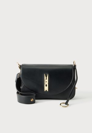 Sac bandoulière en cuir noir avec fermoir en forme de pince à linge dorée et bandoulière réglable avec éléments métalliques dorés sur fond blanc.