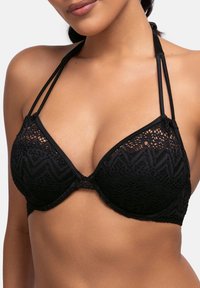 Svart spets-bh med bygel, med geometriskt mönster och justerbara axelband. Mjuk tygkänsla och djupt skuren halsringning.