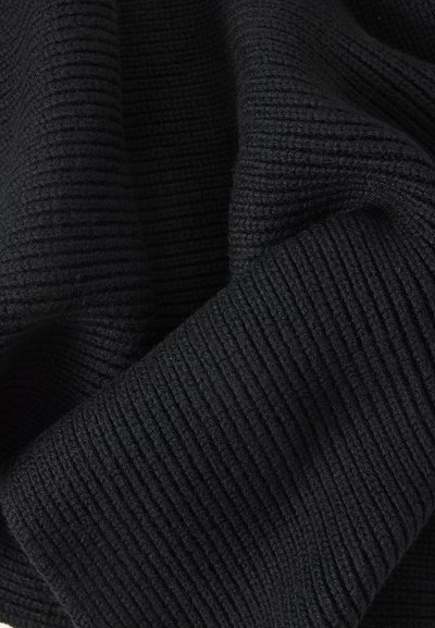 Tissu tricoté côtelé noir avec texture pliée, montrant des détails fins du fil et un motif de couture dense.