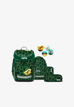Dunkelgrünes Schulranzen-Set mit hellgrünem geometrischem Muster, Dinosaurier-Ansteckern und passenden Federmäppchen auf weißem Hintergrund angeordnet.