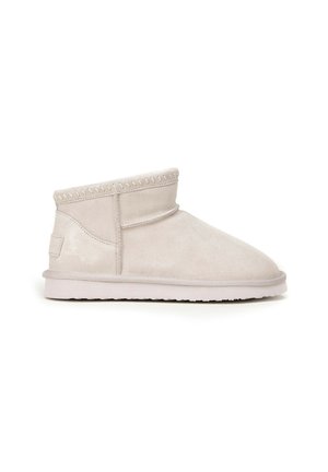 Krótki beżowy zamszowy botek za kostkę z płaską gumową podeszwą, widocznymi przeszyciami i miękkim, zaokrąglonym kształtem noska.