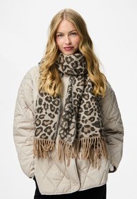 Leopardimustriga sall, mis on valmistatud pehmest kangast ja millel on õhukesed äärised, beeži ja pruuni tooni, kantud kergelt tõmmatud jope peale.