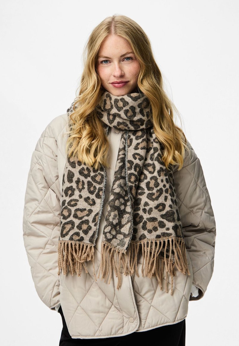 Leopardimustriga sall, mis on valmistatud pehmest kangast ja millel on õhukesed äärised, beeži ja pruuni tooni, kantud kergelt tõmmatud jope peale.