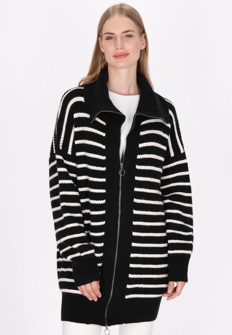 Černobílý pruhovaný cardigan na zip s vysokým límcem, pletenou strukturou a volným střihem. Obsahuje dlouhé rukávy a boční kapsy.