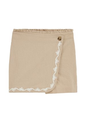 Beige omslagsnederdel med elastisk talje, fastgjort med en brun knap, der har hvid blomsterbroderi langs kanten.