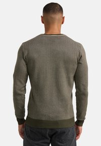 Pulover tricotat de culoare verde măsliniu, cu tivuri și manșete pe margine, având un model texturat și o margine contrastantă la guler.