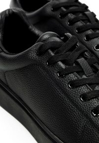 Sneaker nere in pelle testurizzata, con molteplici occhielli, lacci neri piatti e una suola in gomma a profilo basso.