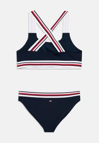 Μπλε μαρινιέρα σετ μαγιό με τοπ τύπου αμάνικο και διασταυρούμενους ιμάντες, με λευκές, κόκκινες και μπλε ρίγες· ταιριαστό κάτω μέρος μπικίνι με ριγωτή μέση.