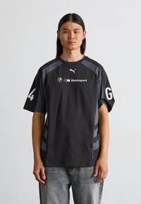 Sort bomuld t-shirt med grå detaljer, featuring rund hals, korte ærmer og hvide logoer. Bemærkelsesværdigt nummer "4" og bogstav "G" på ærmerne.