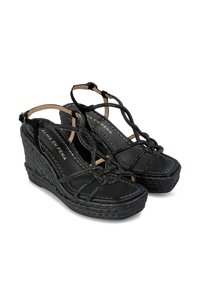 Sandalias de cuña negras con correas entrecruzadas, tela texturizada y suela de yute trenzado. Planta interior negra lisa con detalle de costura blanca.