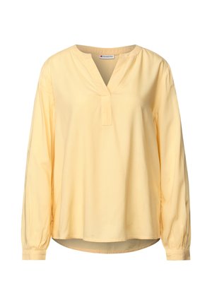 Blouse jaune à manches longues avec décolleté en V, poignets froncés et coupe décontractée. Fabriquée en tissu lisse avec des détails de design minimaux.