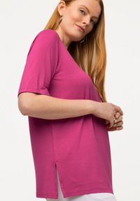 T-shirt fucsia a maniche corte con una vestibilità rilassata, dotata di spacchi laterali e una texture di tessuto morbida e leggera.