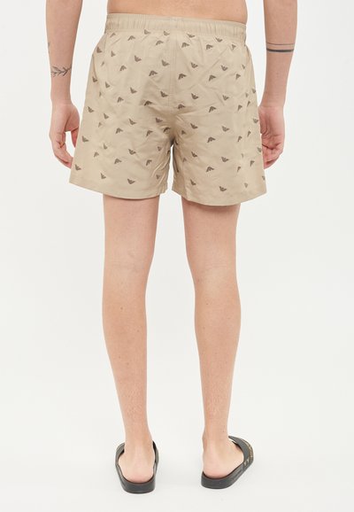 Shorts da bagno beige con motivo a griglia marrone scuro. Vita elasticizzata, materiale leggero e taglio sopra il ginocchio.