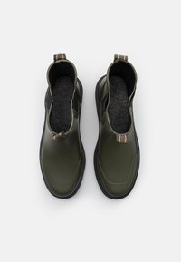 Bottes de cheville imperméables vertes avec une texture lisse, semelle en caoutchouc renforcée et doublure en tissu, dotées d'une petite languette à l'arrière.