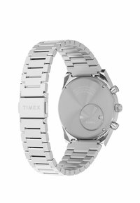 Reloj de acero inoxidable plateado con una pulsera de eslabones, esfera redonda limpia, botones de cronógrafo y fondo grabado con el nombre de la marca.