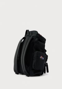 Rucsac negru cu design structurat, compartimente multiple, părți laterale din plasă și logo de brand roșu și albastru pe buzunarul frontal. Material durabil.