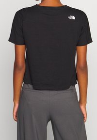 Mustat, lyhythihaiset t-paidat, joissa on lyhennetty malli. Ominaisuuksiin kuuluu vaakasauma hartioiden läheisyydessä ja pieni valkoinen logo takana.