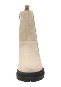 Beige Wildleder-Ankle-Boot mit schwarzer, grober Gummisohle, seitlichem Reißverschluss und Zuglasche, von der Frontansicht auf weißem Hintergrund dargestellt.