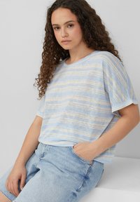 Lichtblauw gestreept, kortpoloshirt van zachte stof, gecombineerd met lichtblauwe denim shorts. Relaxte pasvorm, ronde hals met subtiele textuur.