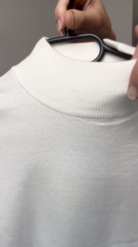 White short-sleeve shirt with a ribbed high collar, displayed on a hanger. The fabric appears soft with a smooth, lightweight texture.