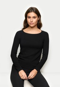 Schwarzes langärmliges Oberteil mit rundem Ausschnitt, figurbetontem Design, glatter Textur und aus elastischem Stoff, kombiniert mit schwarzen Leggings.