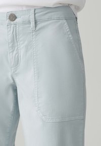 Helle blaue Hose aus weichem Stoff, mit einem klassischen Bund, seitlichen Taschen und flachen Nähten für einen sauberen, maßgeschneiderten Look.