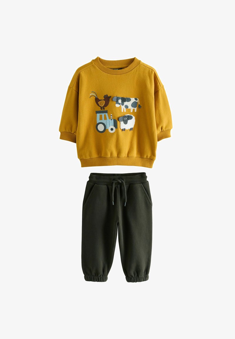 Senfgelbes Sweatshirt mit Applikationen von Farmtieren und einem Traktor, kombiniert mit dunkelgrünen Jogginghosen mit elastischen Bündchen und Kordelzug.