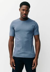 Īsās piedurknes t-krekls ar apaļu kakla izgriezumu, gaiši zilā kokvilnas maisījumā. Gluda tekstūra, piegulošs dizains un smalkas šūšanas detaļas gar apakšmalu.