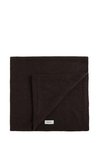 Coperta di lana marrone con superficie morbida e testurizzata. L'angolo piegato rivela il tessuto interno. Etichetta cucita sul bordo. Forma rettangolare.