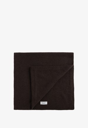 Couverture en laine brune avec une surface douce et texturée. Le coin replié révèle le tissu intérieur. Étiquette cousue sur le bord. Forme rectangulaire.