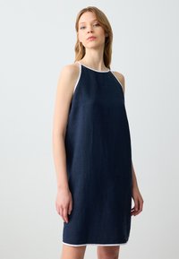 Abito in lino blu navy con rifiniture bianche, design senza maniche, vestibilità ampia, lunghezza al ginocchio. Texture liscia e silhouette semplice.