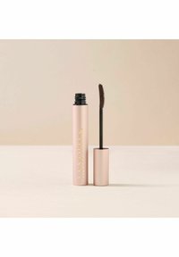 Mascara dans un tube rose clair mat avec des lettres dorées, comportant une brosse noire à poils courts. Le bouchon du tube est lisse.